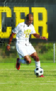 Andrew kicks soccer ball in UMBC gear