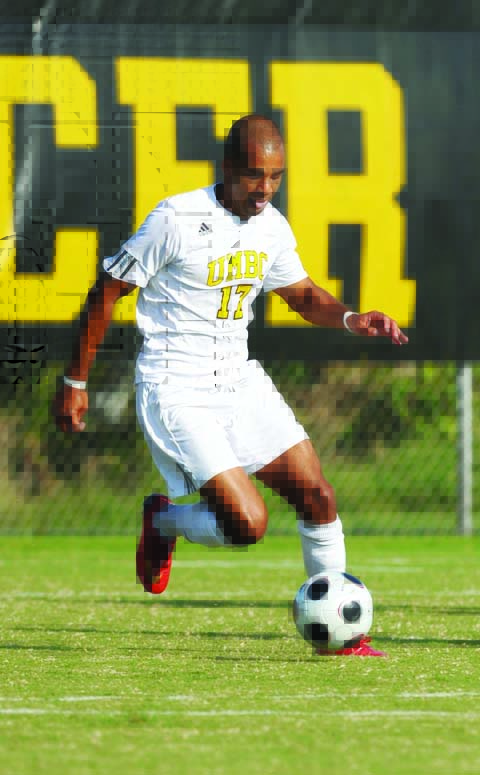 Andrew kicks soccer ball in UMBC gear