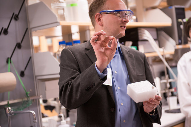 man with toothpick and protective glasses in lab