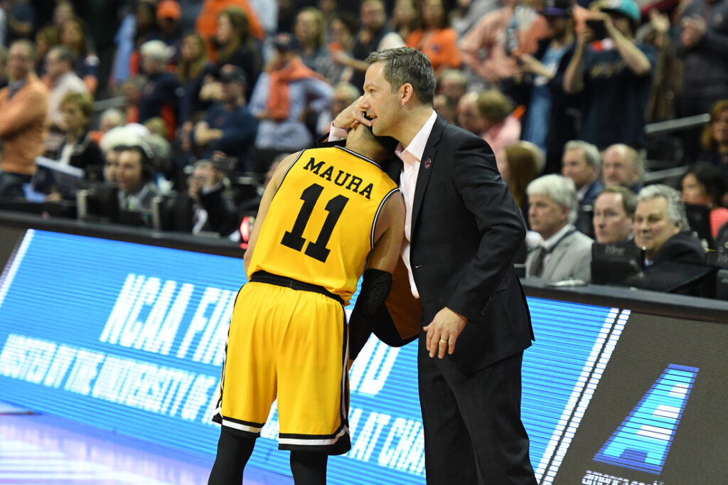 Coach hugs basketball player in yellow jersey.