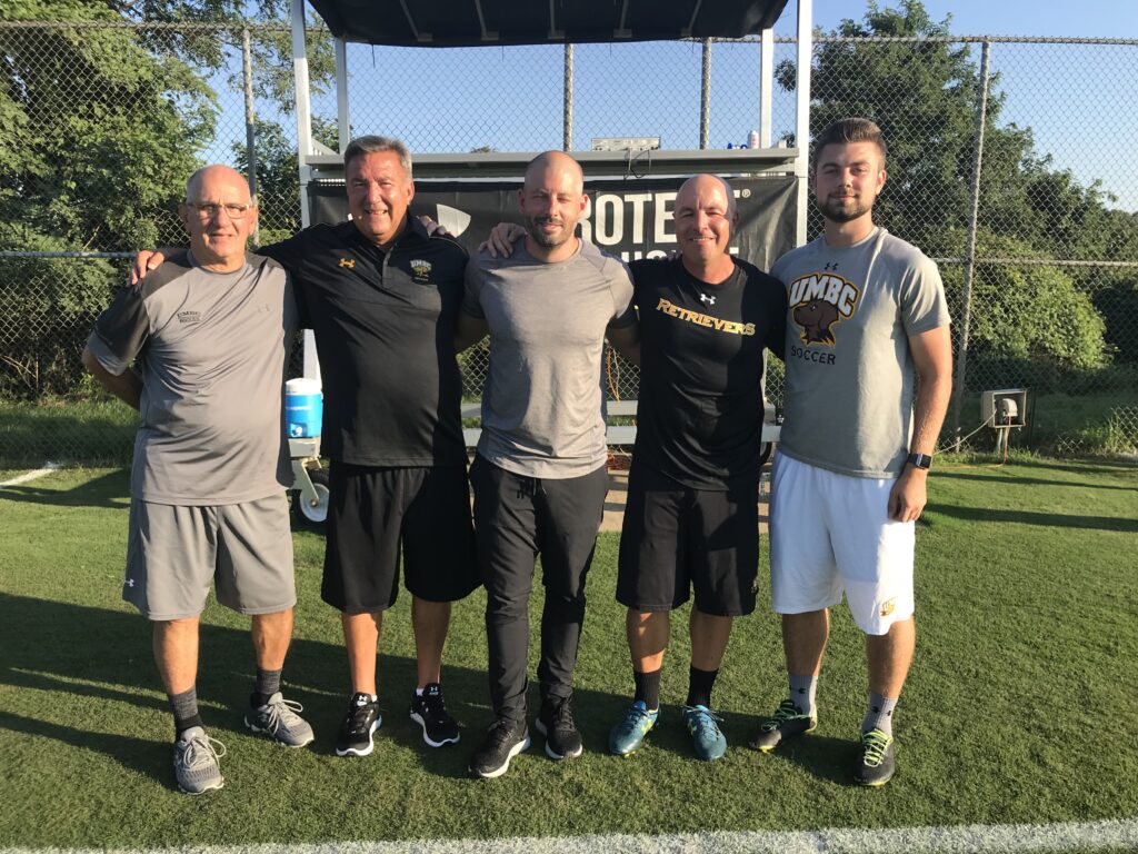 a group of men stand shoulder to shoulder in athletics gear