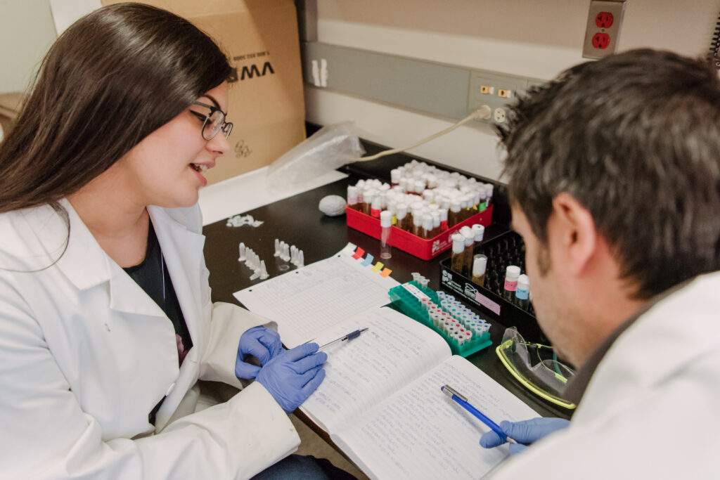 Two researchers examining a lab notebook