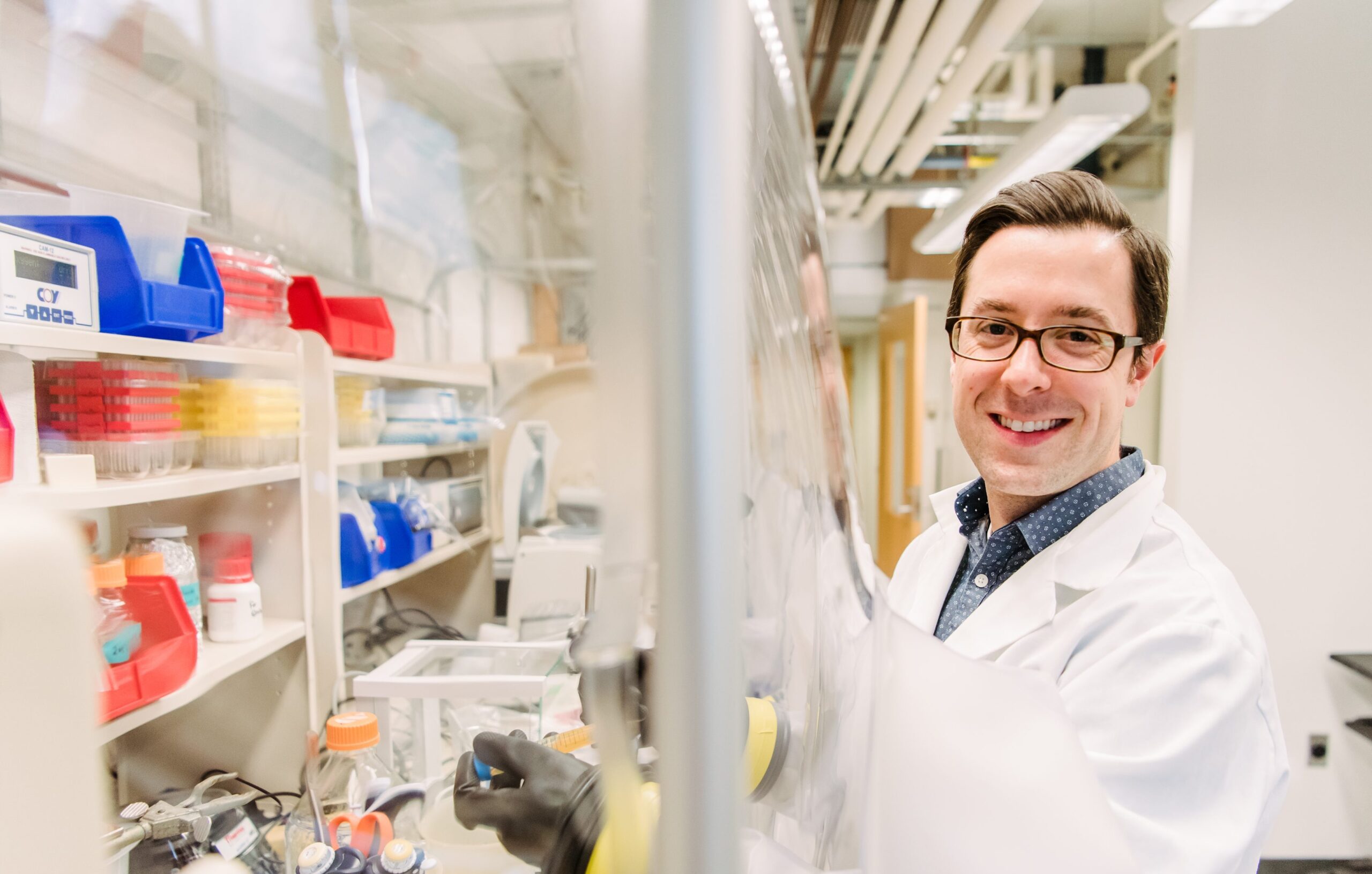 Aaron Smith working at lab bench, smiling at camera.