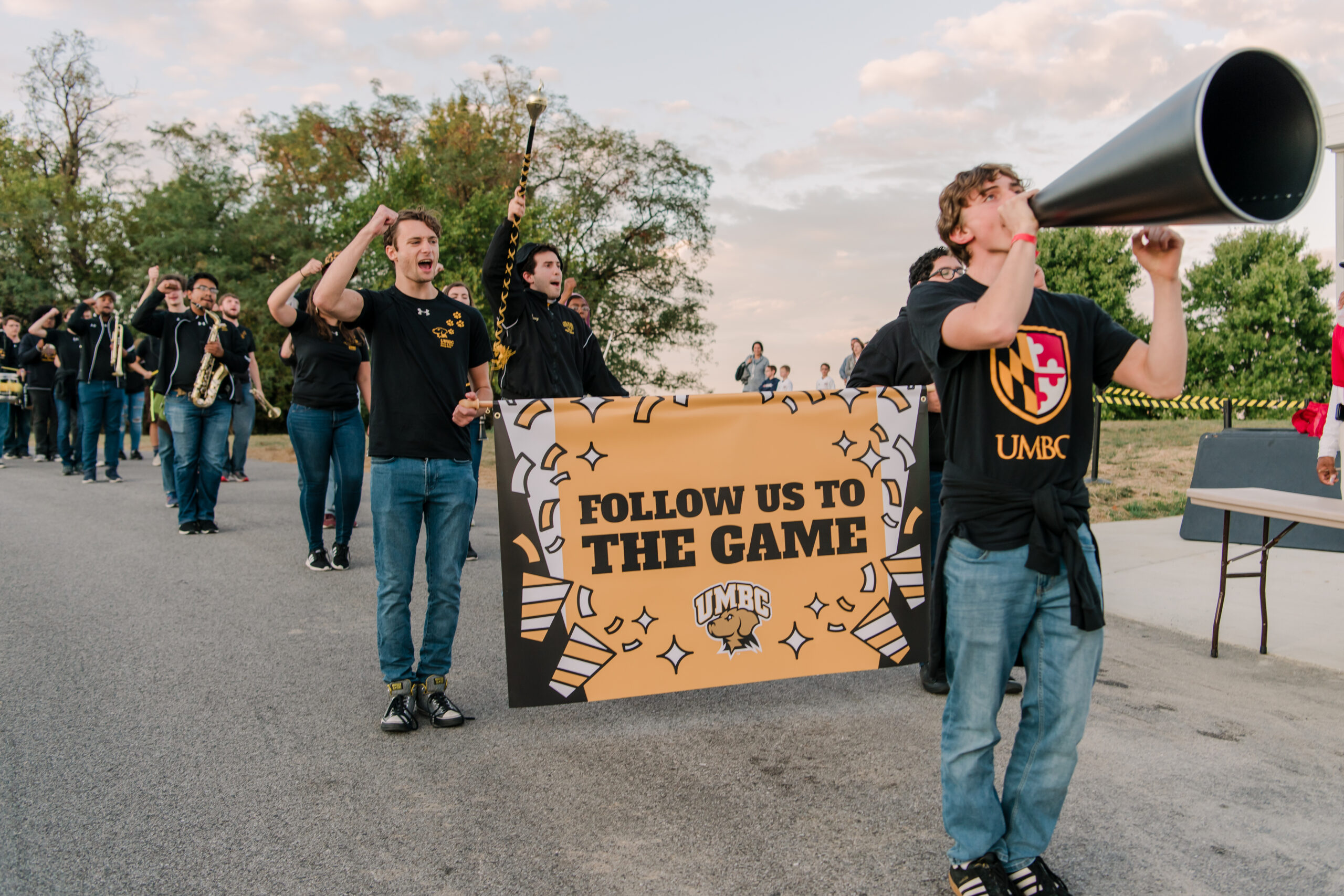 UMBC marching band with follow us to the game banner