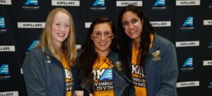 Three girls holding America East trophy.