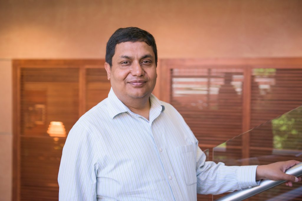 Portrait of man in a dress shirt with arm on a staircase railing.