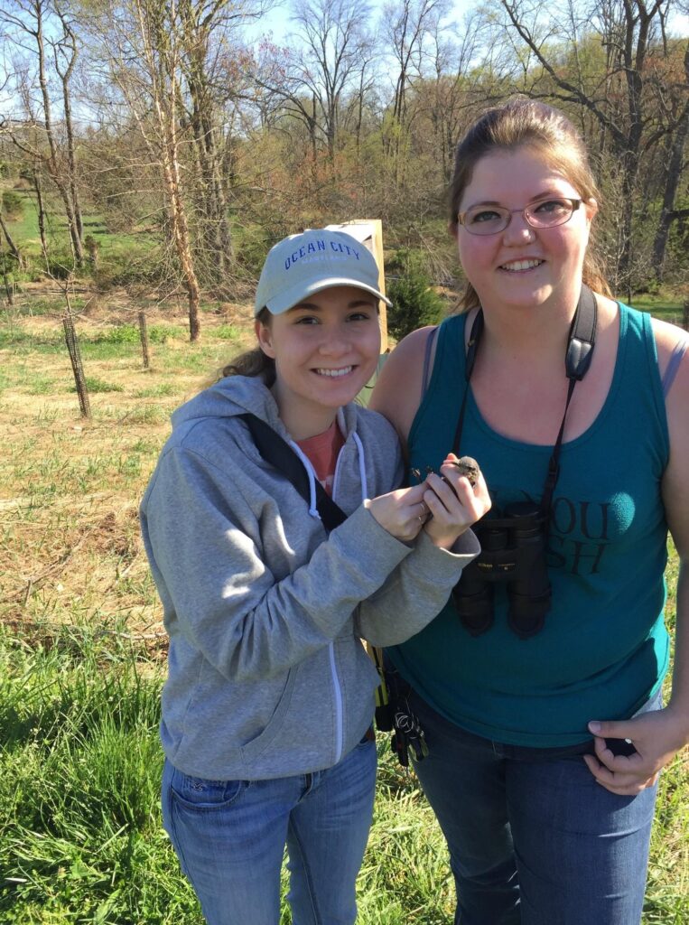 two women outdoors, one holding a bird
