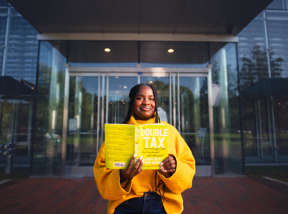 Writer Anna Gifty Opoku-Agyeman holdinh her book "The Double Tax: How Women of Color are Overcharged and Underpaid" (Credit: Corban Swain Productions).