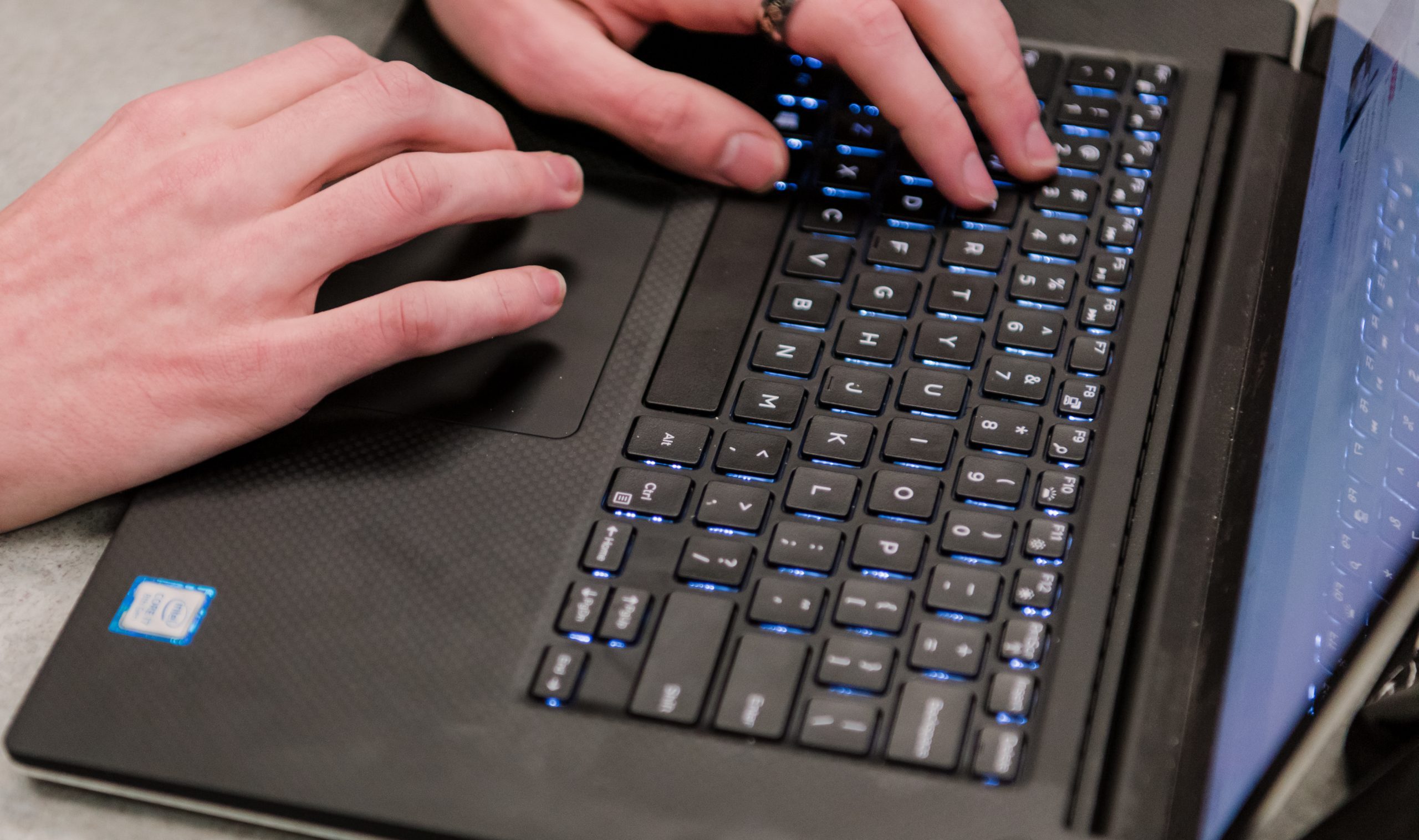 Hands typing on a black keyboard.