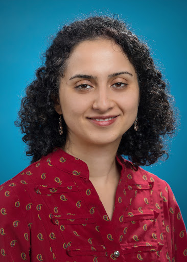 Portrait of a middle-aged woman with curly shoulder-length hair, wearing a red shirt with print.