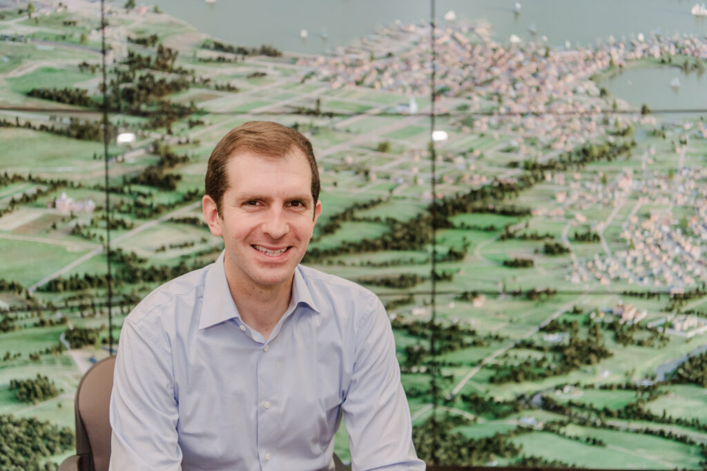 Man in front of large screen showing mostly green areas along a waterfront.