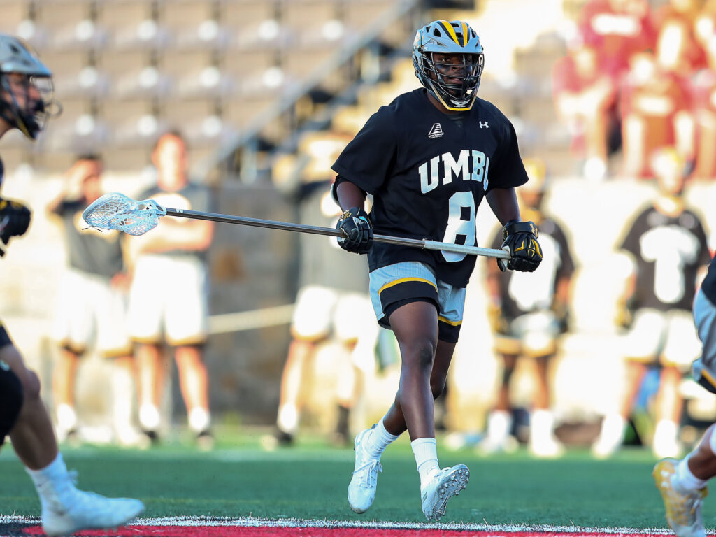 Lacrosse player on a field, wears a uniform reading
