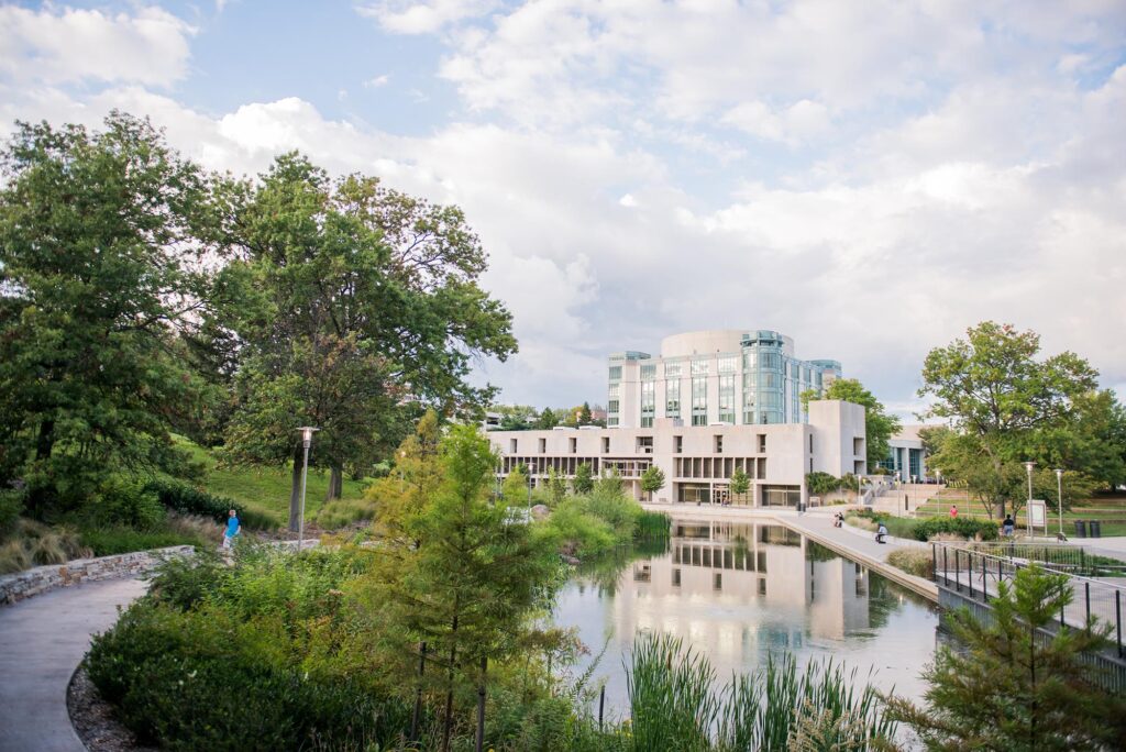 UMBC's campus in the fall, featuring the AOK Library and its reflection in a pond.