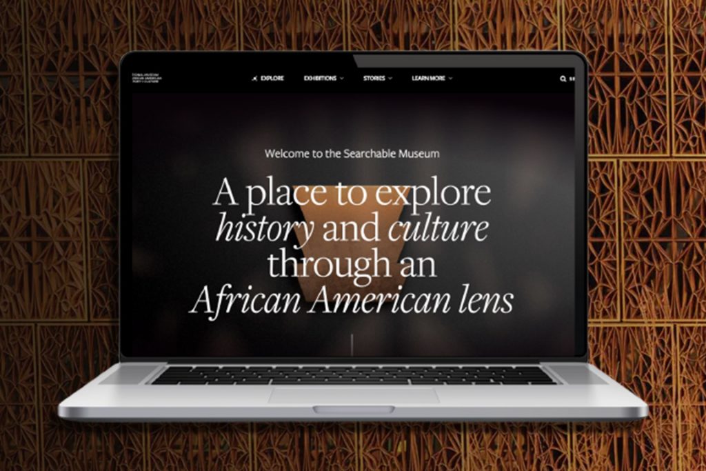A photo of the Searchable Museum interface and introductory slide on the screen of a laptop computer. The background is a brown pattern.