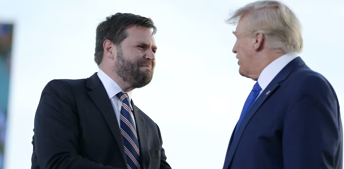 Two people dresses in suits shake hands.