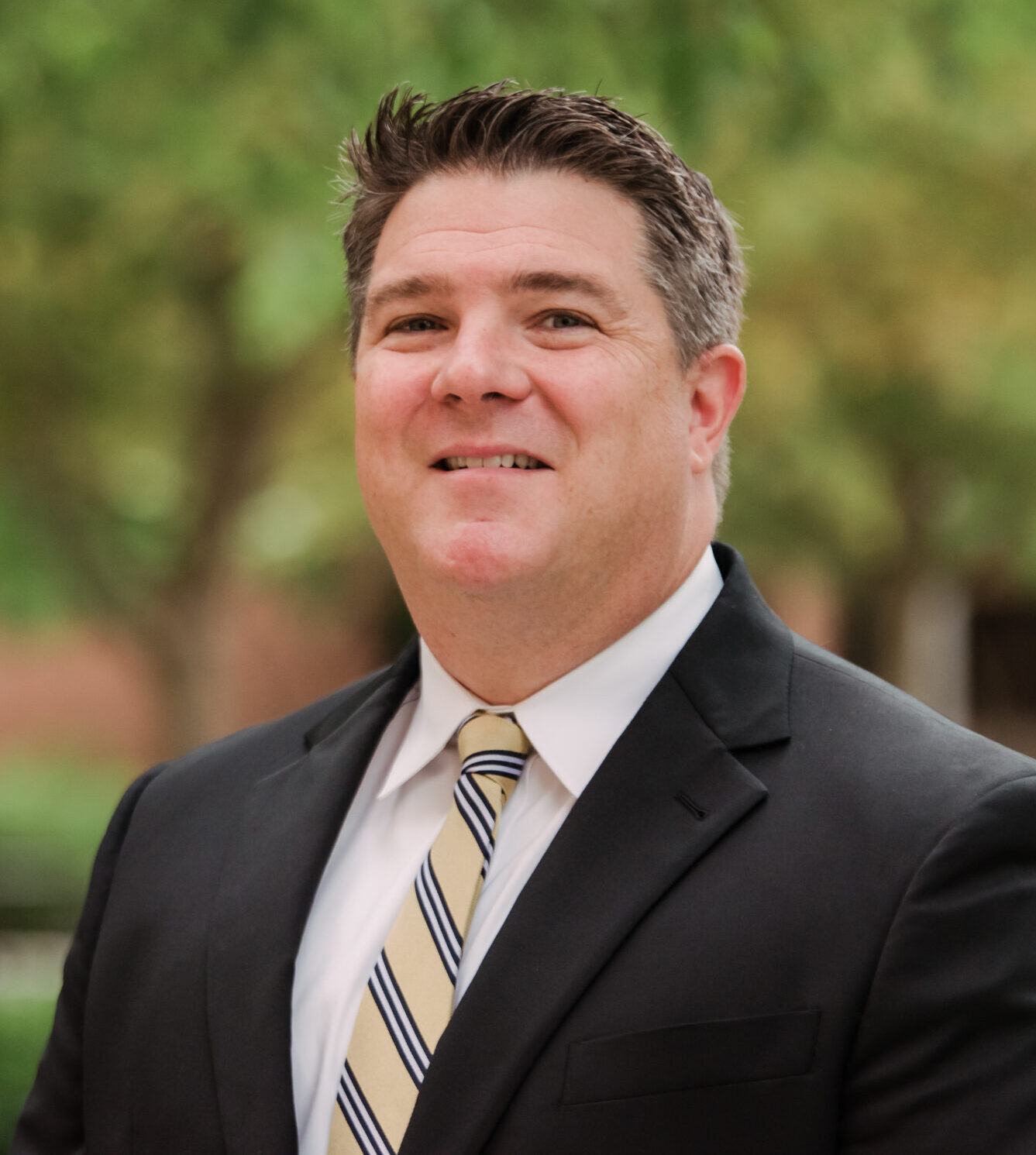 Man smiling for headshot in suit outside