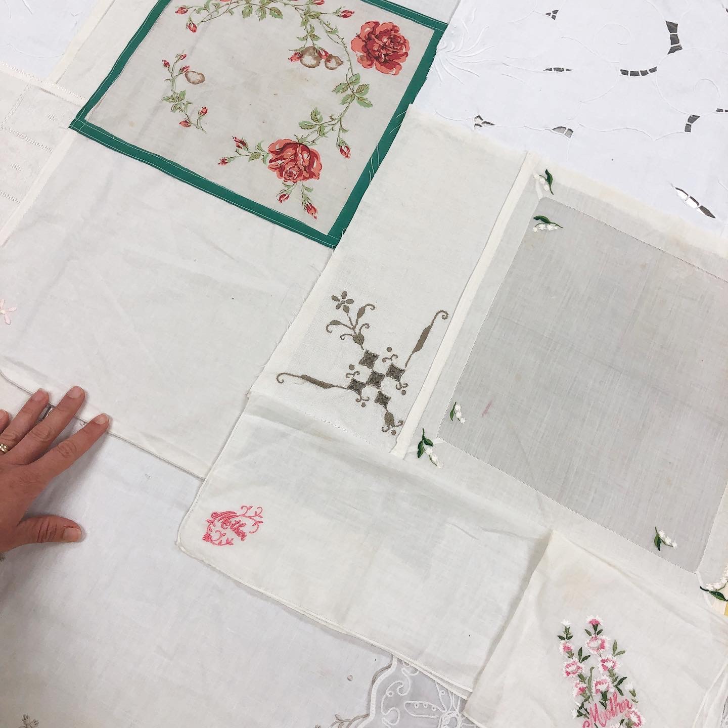Embroidered napkins sewn together with a hand touching the fabric.