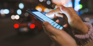 A cellphone being held by a pair of hands and being typed into