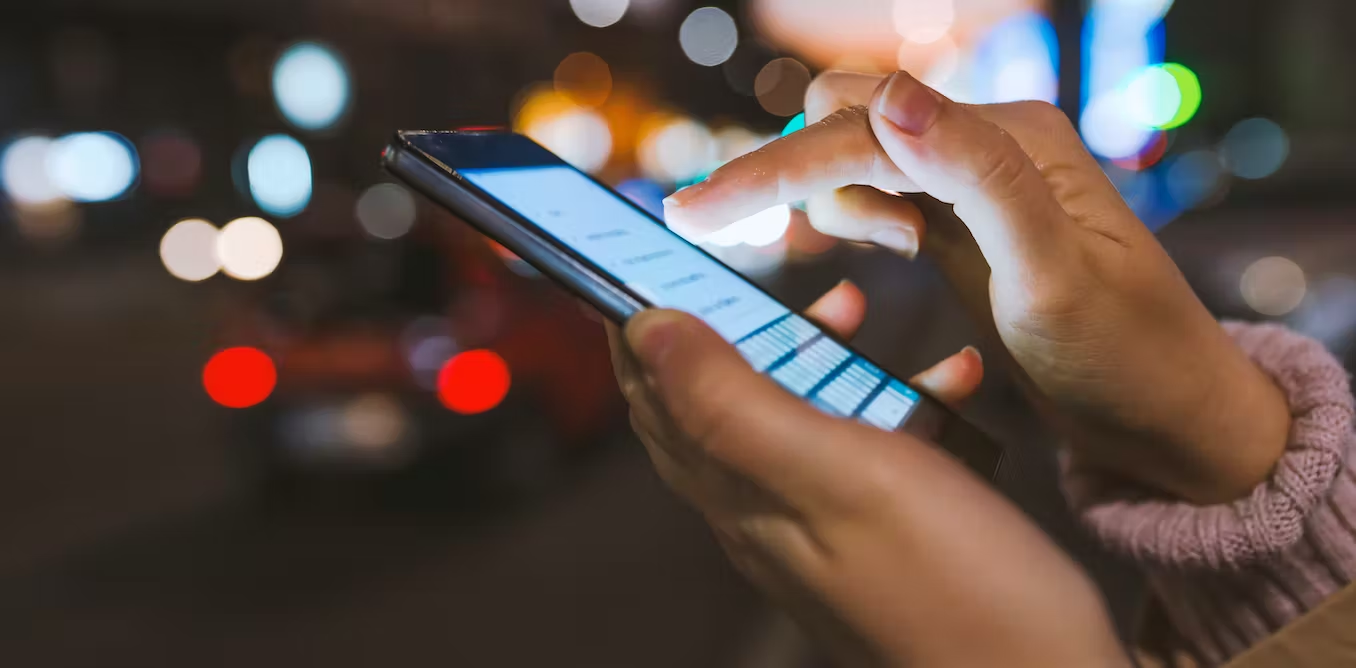 A cellphone being held by a pair of hands and being typed into