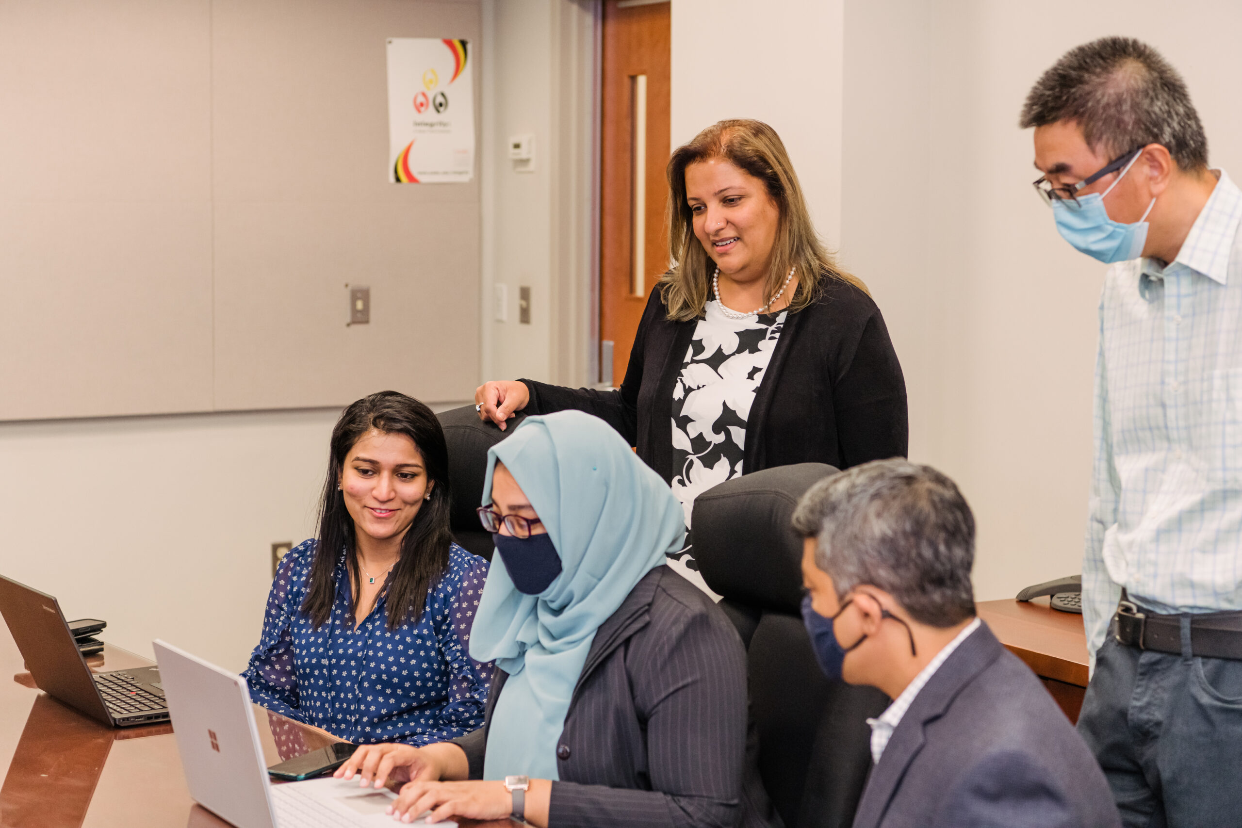 Some of the UMBC iHARP team observes research being done on a shared computer screen.
