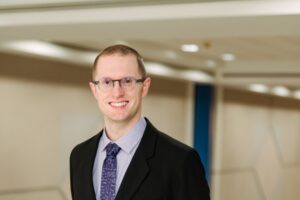 Man smiles at camera, inside of building.