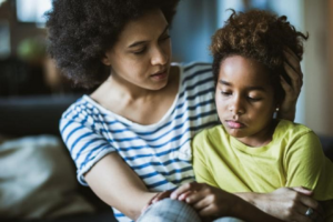 A Black mother holds a Black child.