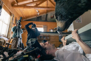 in a behind the scenes shot on a film set, a man fends off a pretend bear with a door