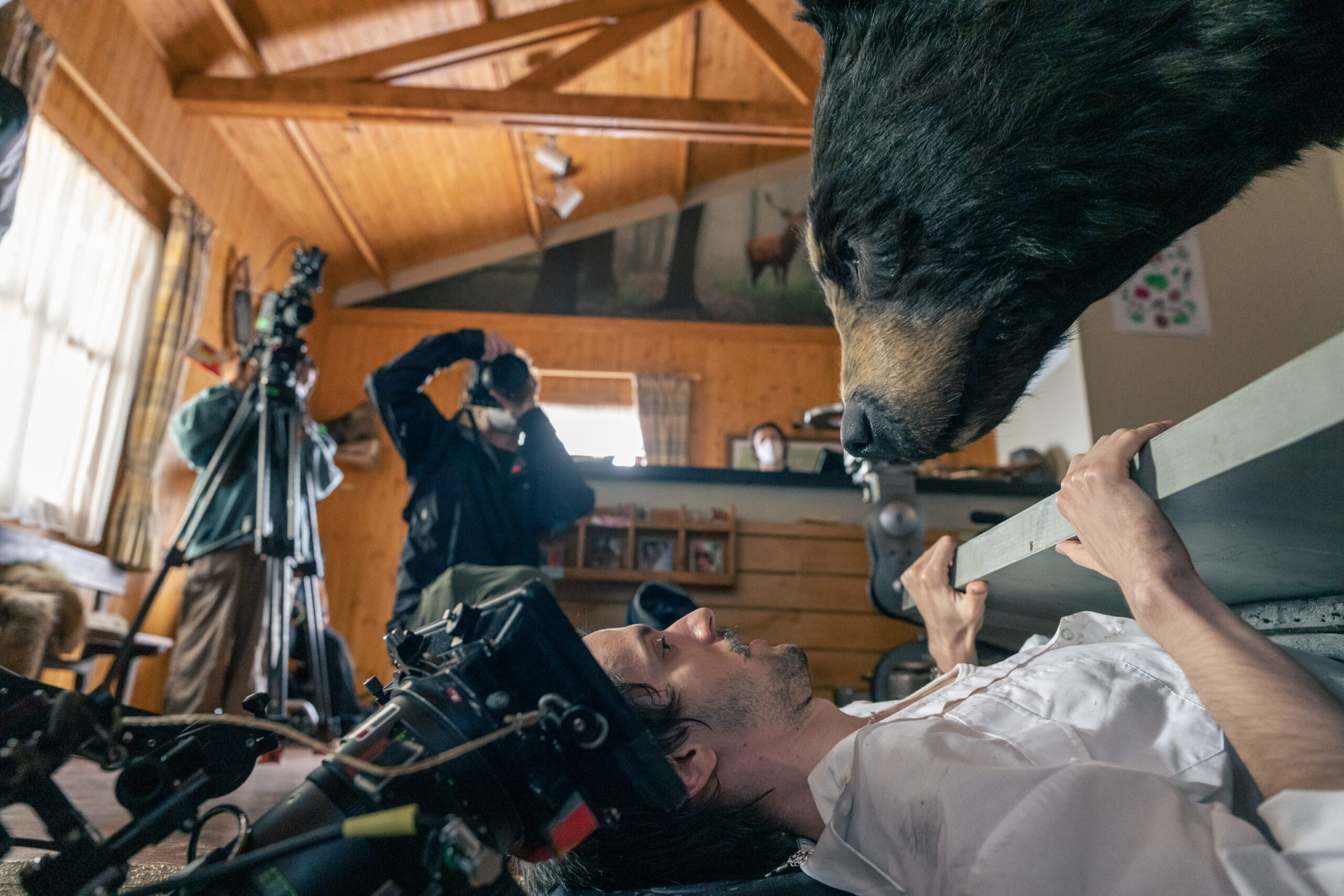 in a behind the scenes shot on a film set, a man fends off a pretend bear with a door
