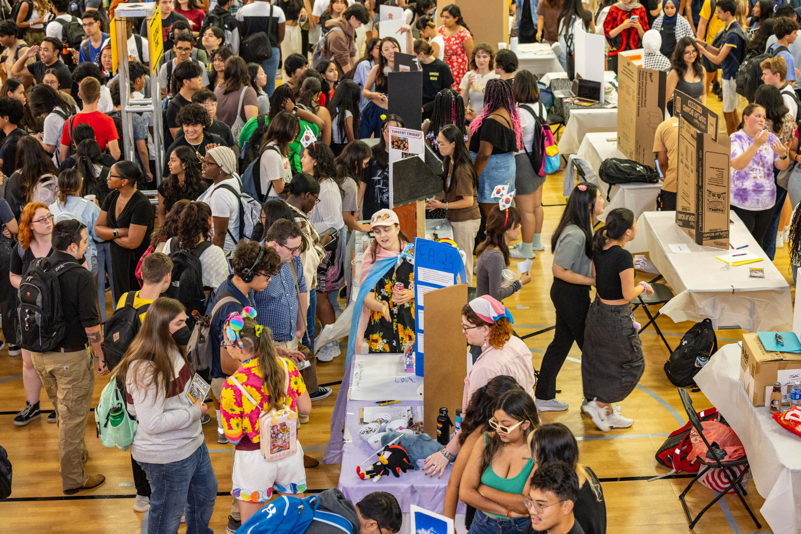Students talk to each other about clubs in a large room.