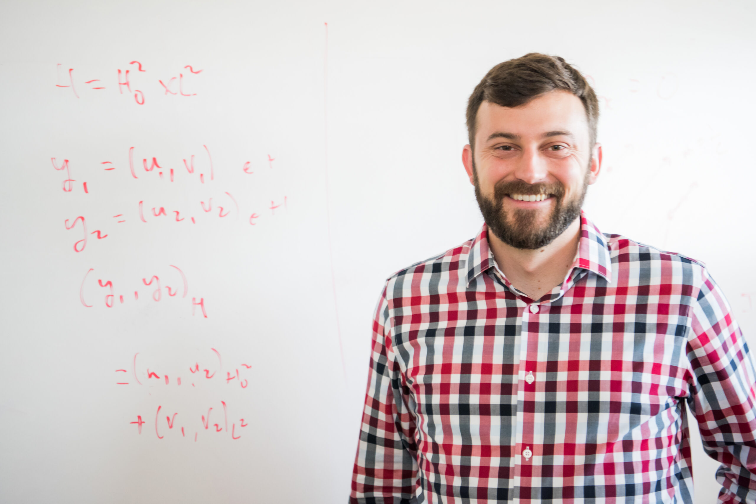 portrait of man standing in front of whiteboard with equations