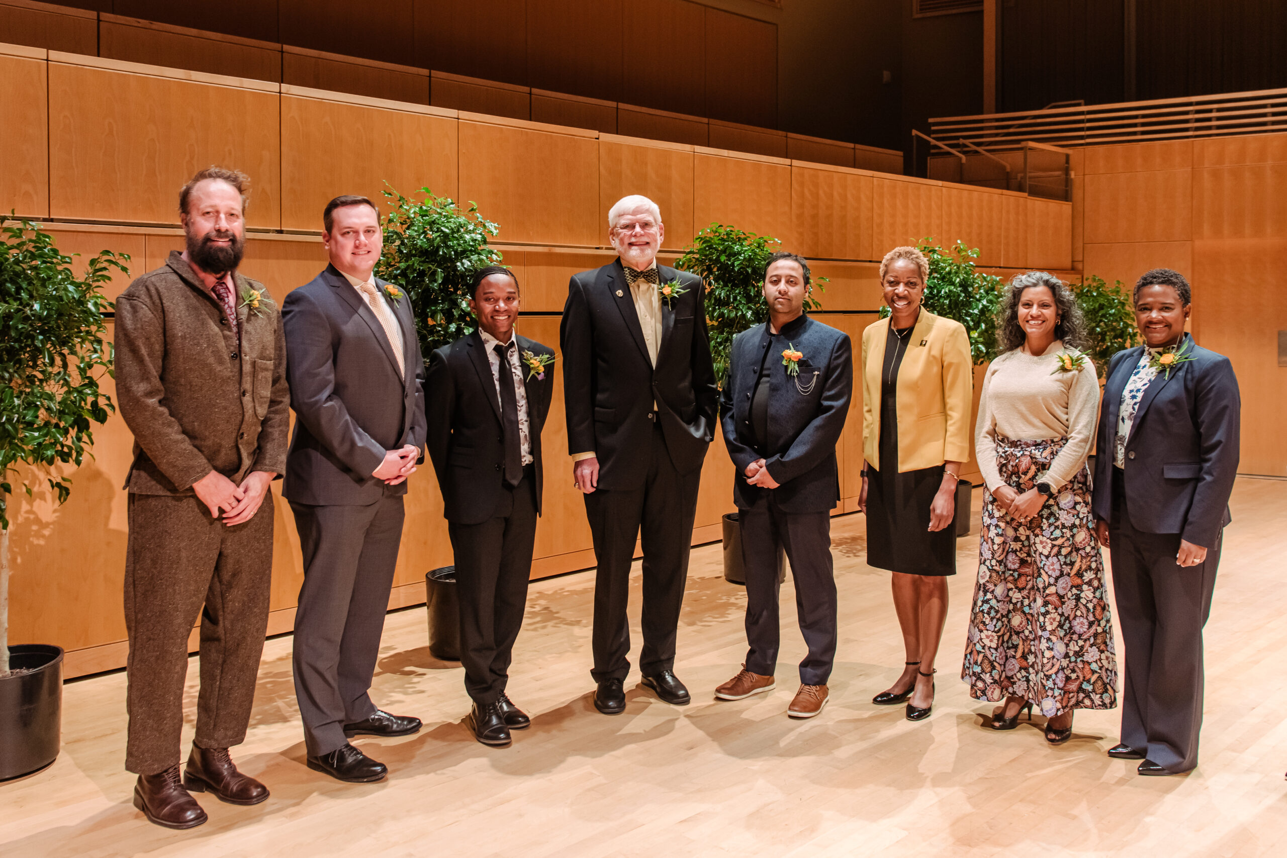 a group of alumni award winners stand together on a stage