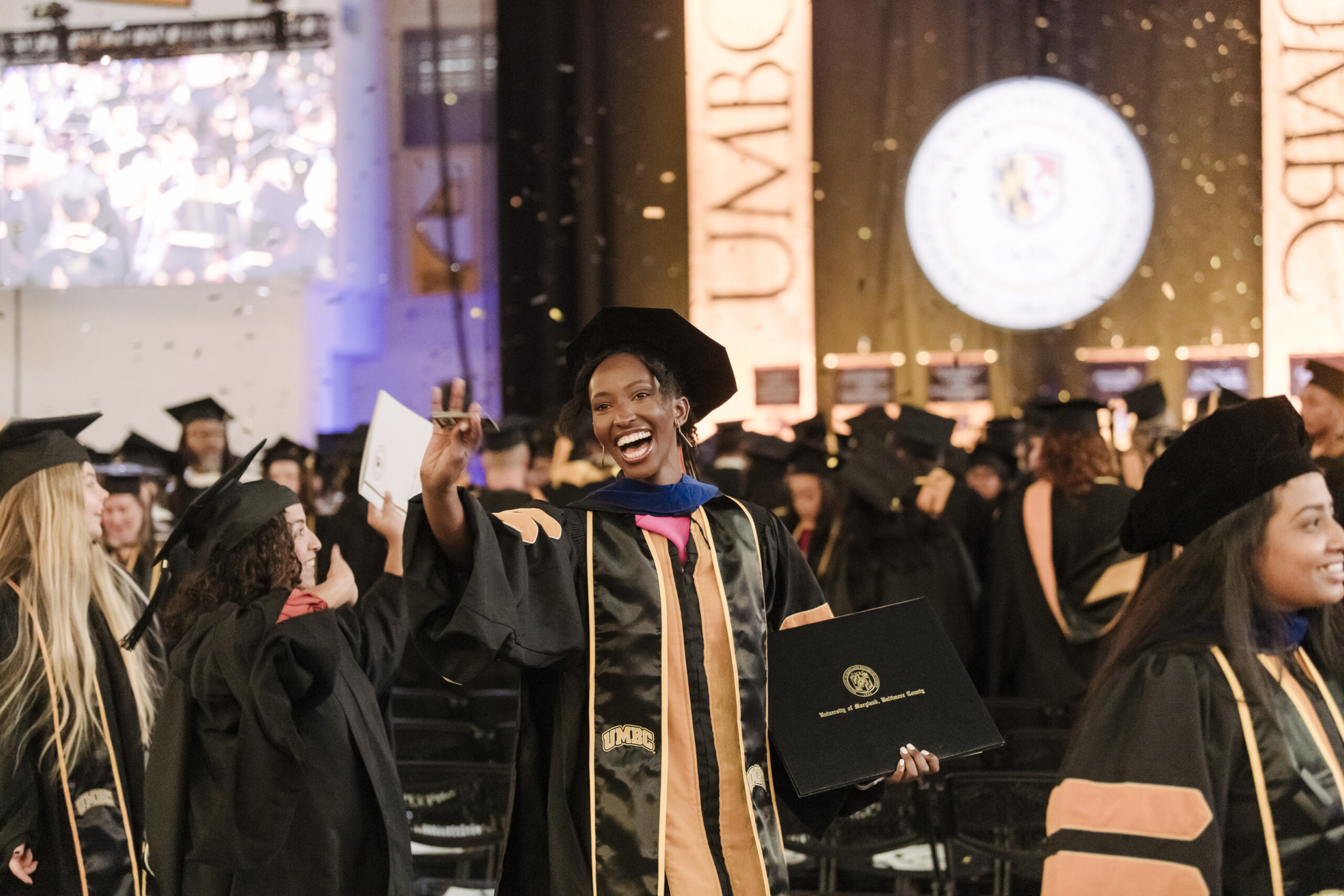 A graduate processes out among other studies smiling