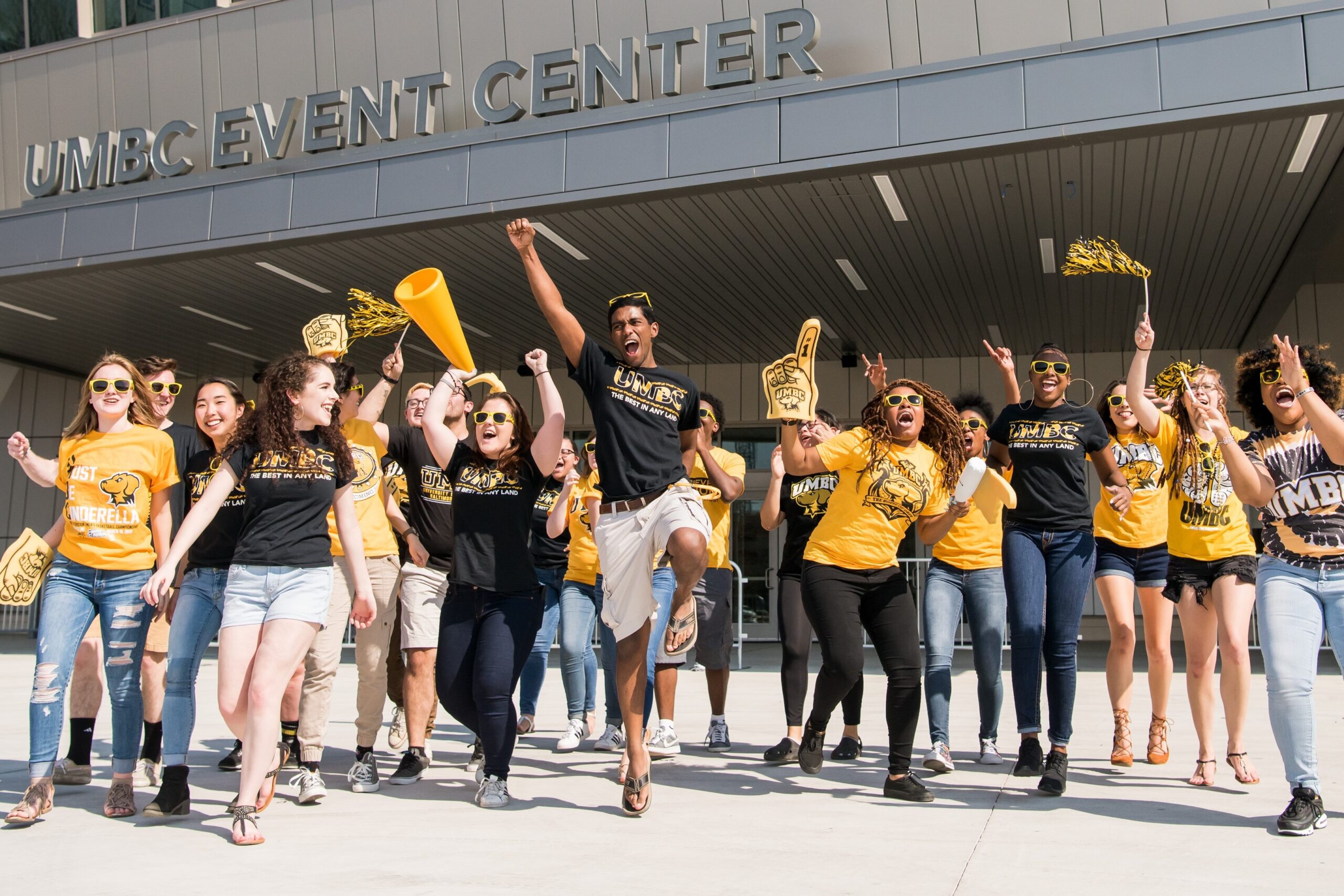 a large group of students wearing black and gold waving flags and celebrating