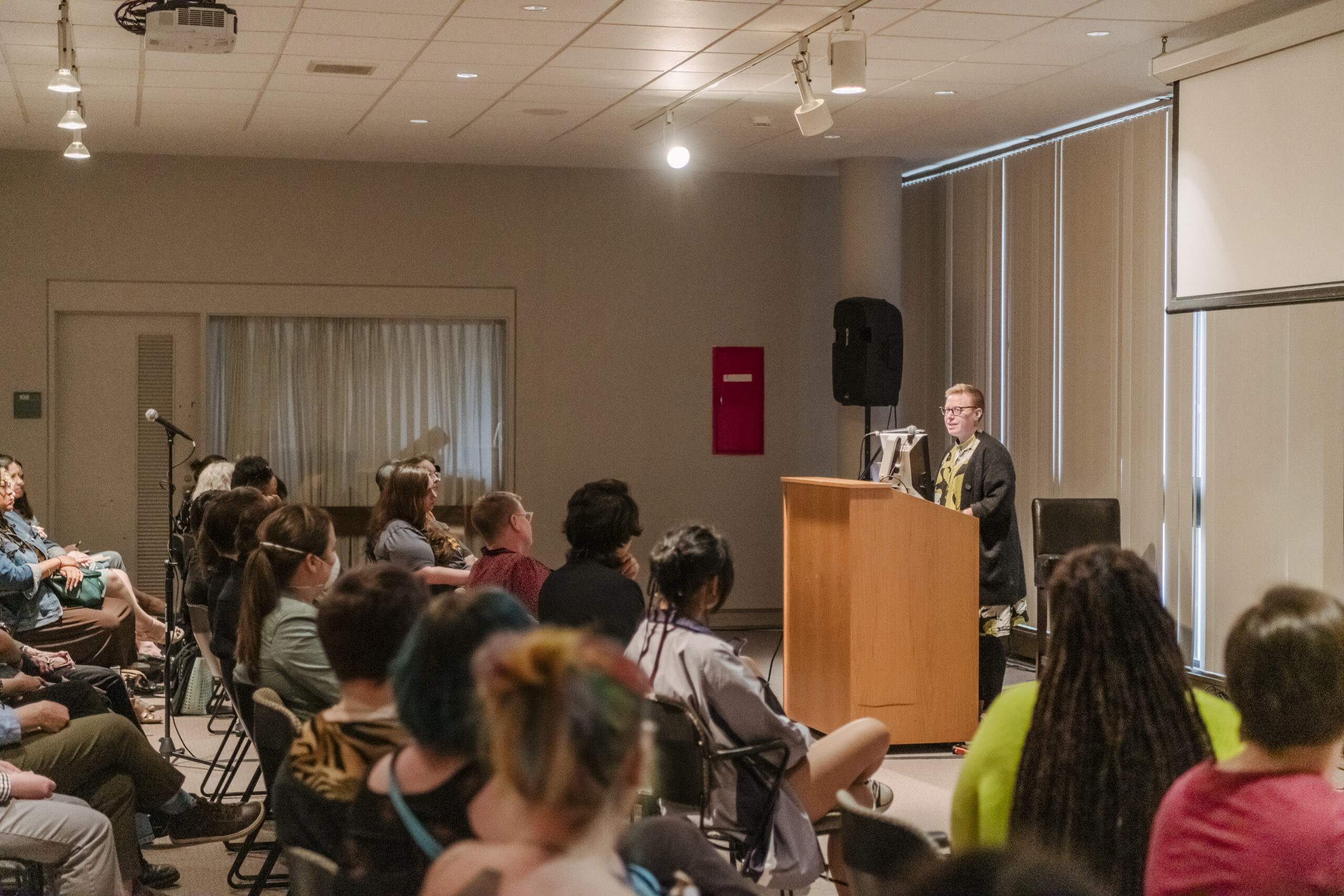 An adult speaks in front of a crowd