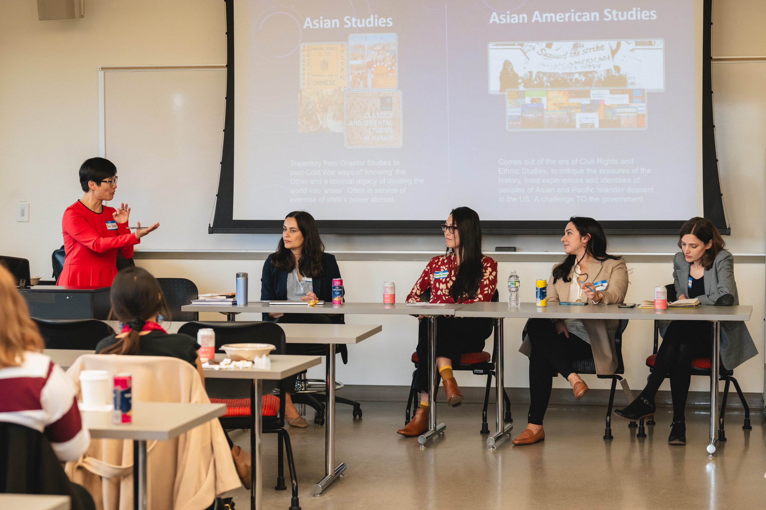 A panel of professors talking with a projector screen behind them