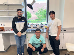 Three male students pose in a lab.
