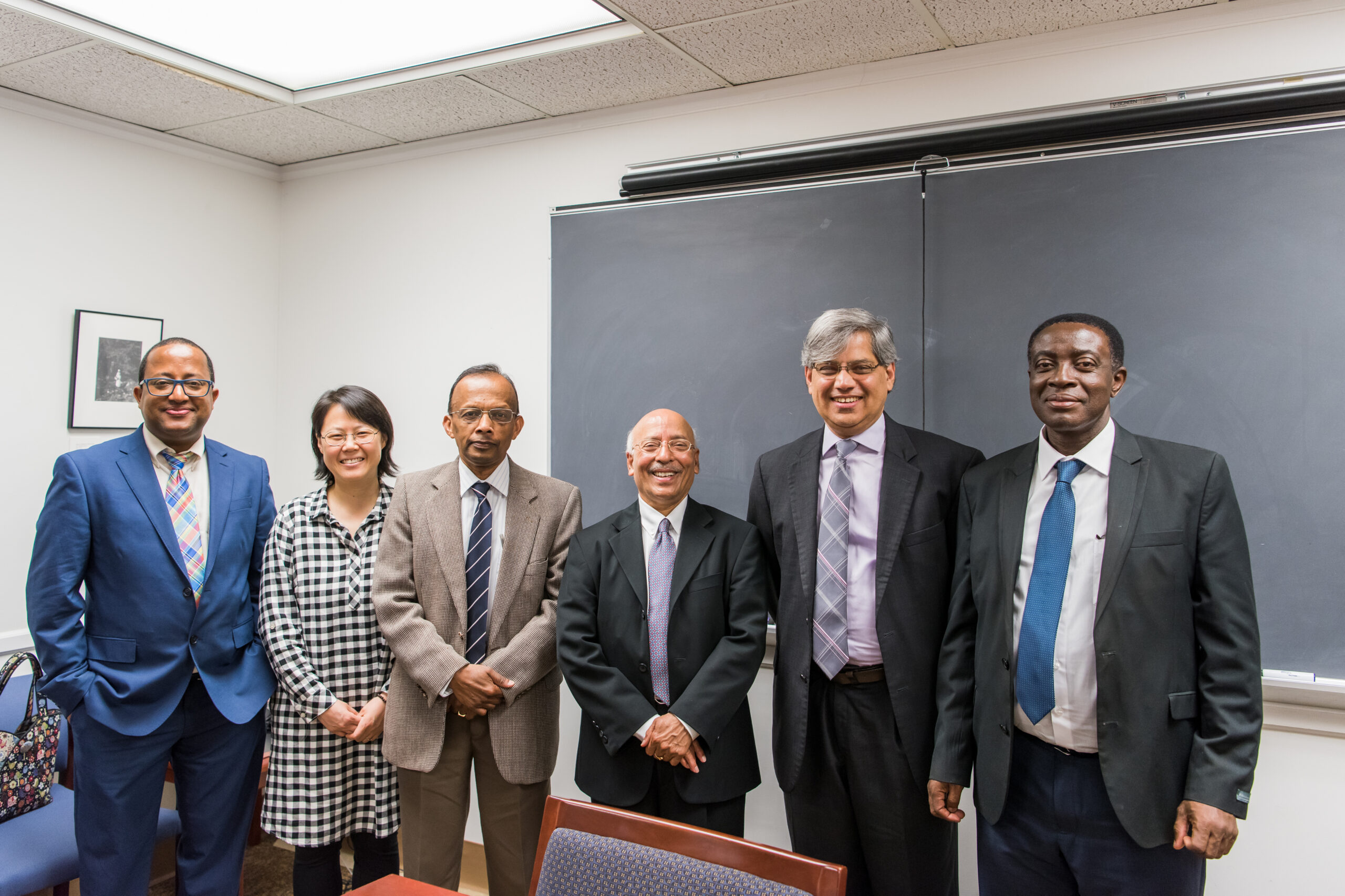 group photo of six people; chalkboard in the background