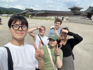 a group of young people make the peace sign and stand in front of the National Palace Museum of Korea