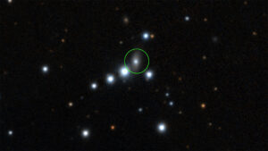 black background; many white and reddish dots showing stars, some quite bright in the center region. One right in the center is outlined with a thin green circle.