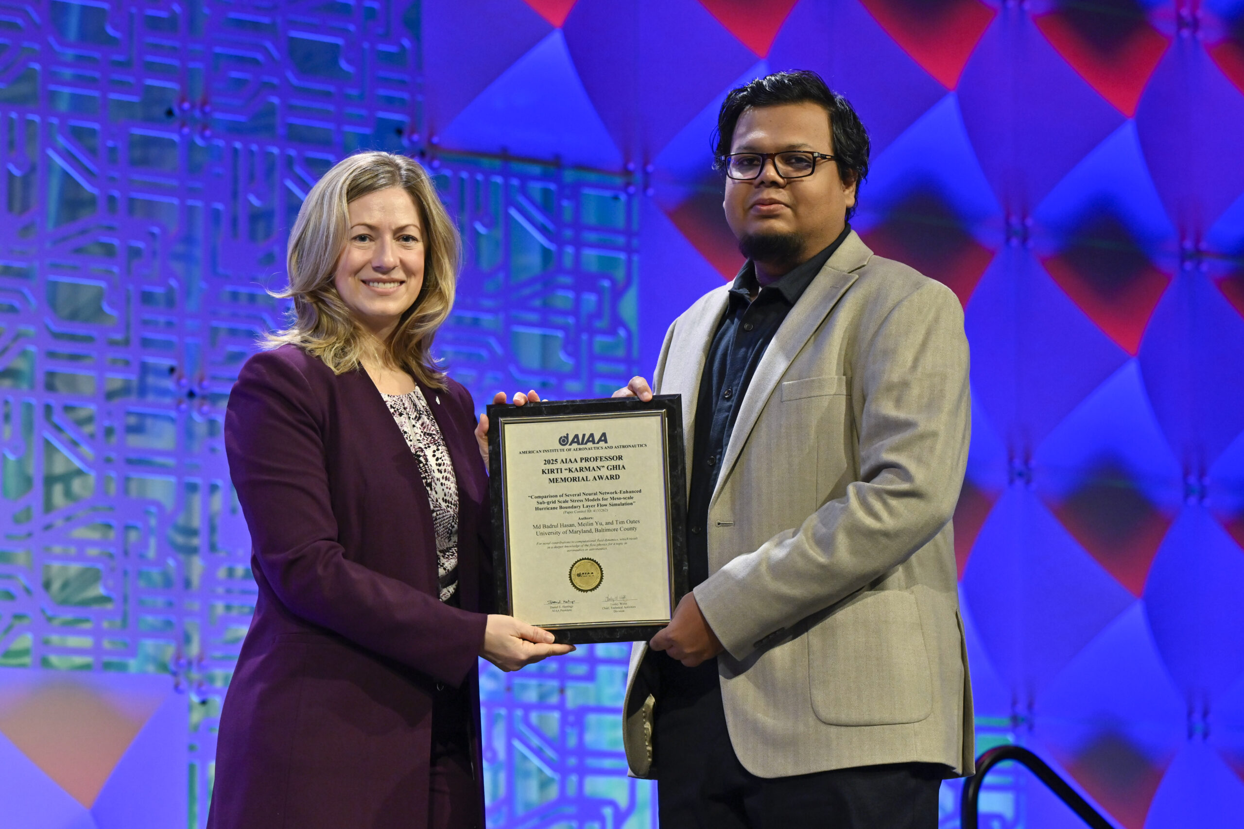 A woman presents a framed certificate to a man in a suit jacket.