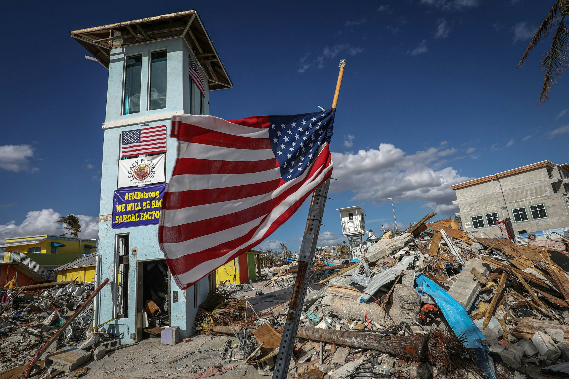 An U.S. flag flies on a makeshift pole on a mound of debris from a natural disaster