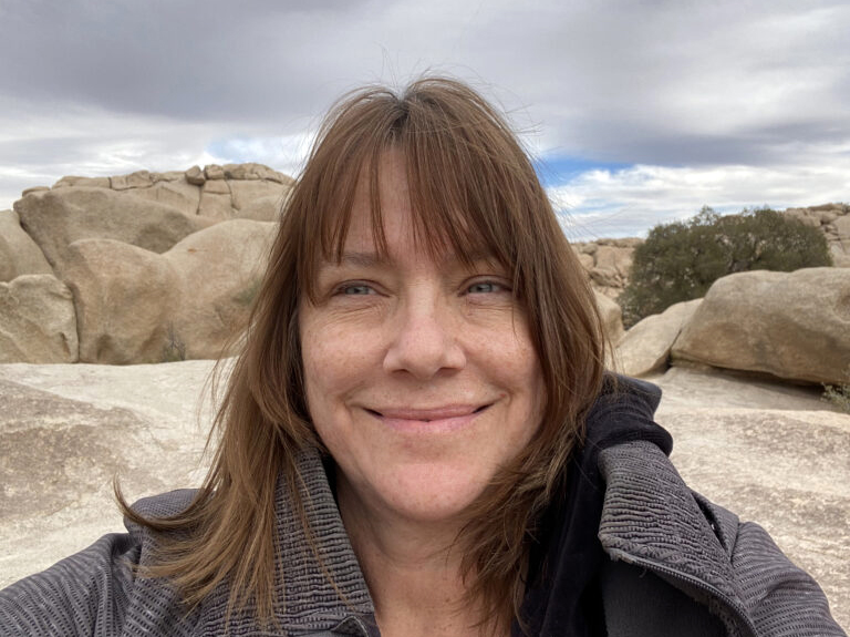 Jayme McLellan, a white woman with brown hair, poses against a rocky background.