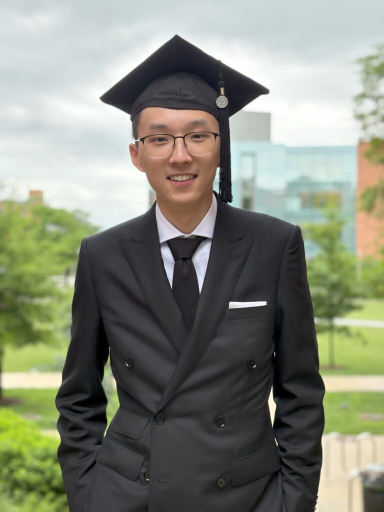 Robert Barry a college student headed to Oxford wears a black suit and a black mortar board stands outside