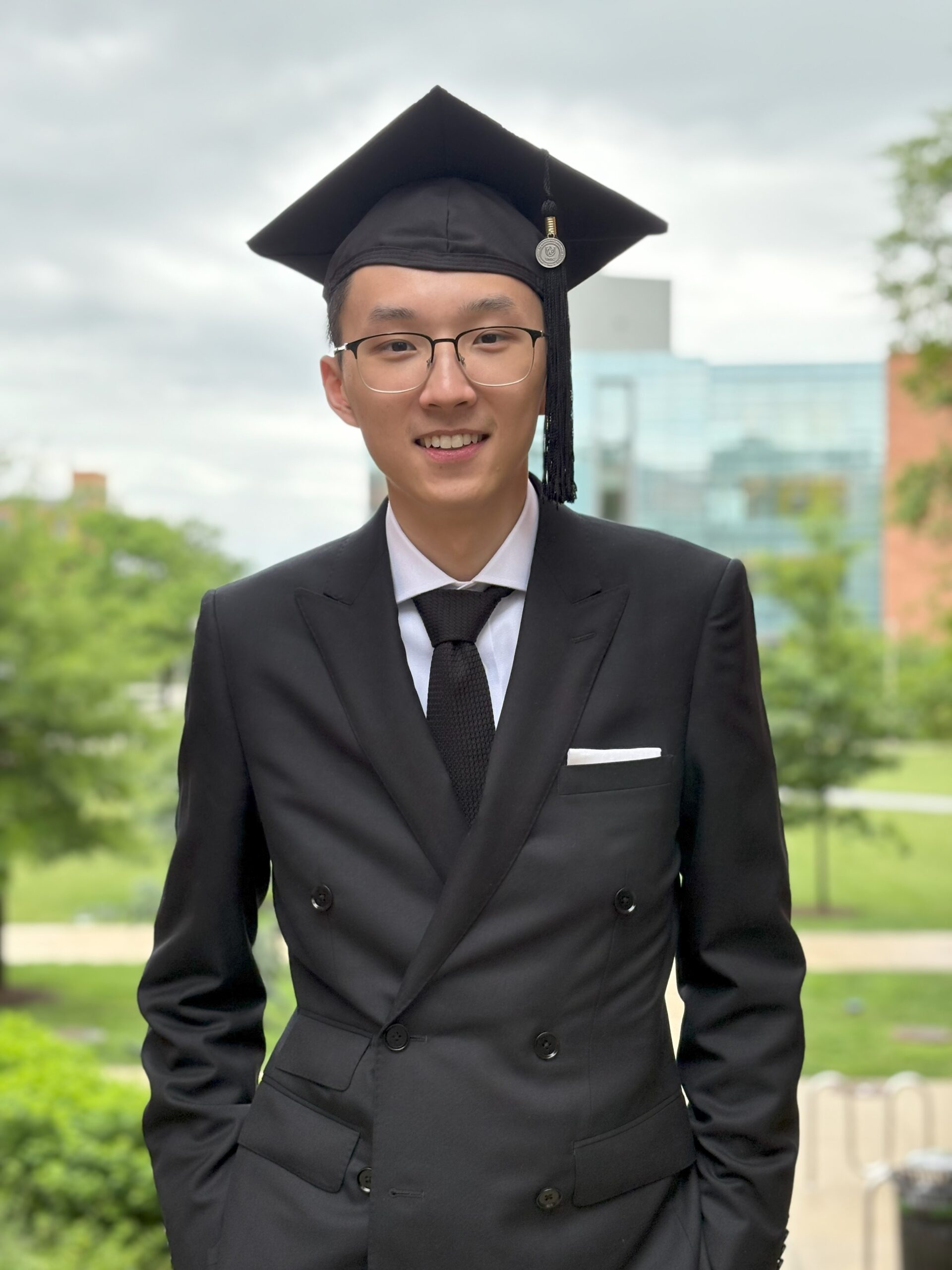 Robert Barry a college student headed to Oxford wears a black suit and a black mortar board stands outside
