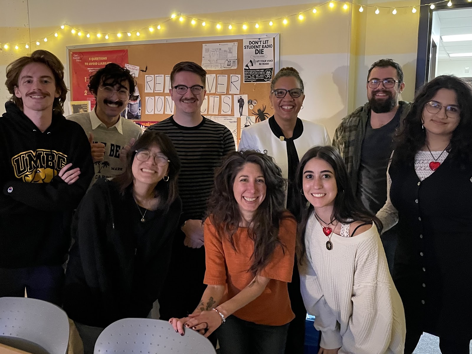 Group of nine people standing in a newsroom