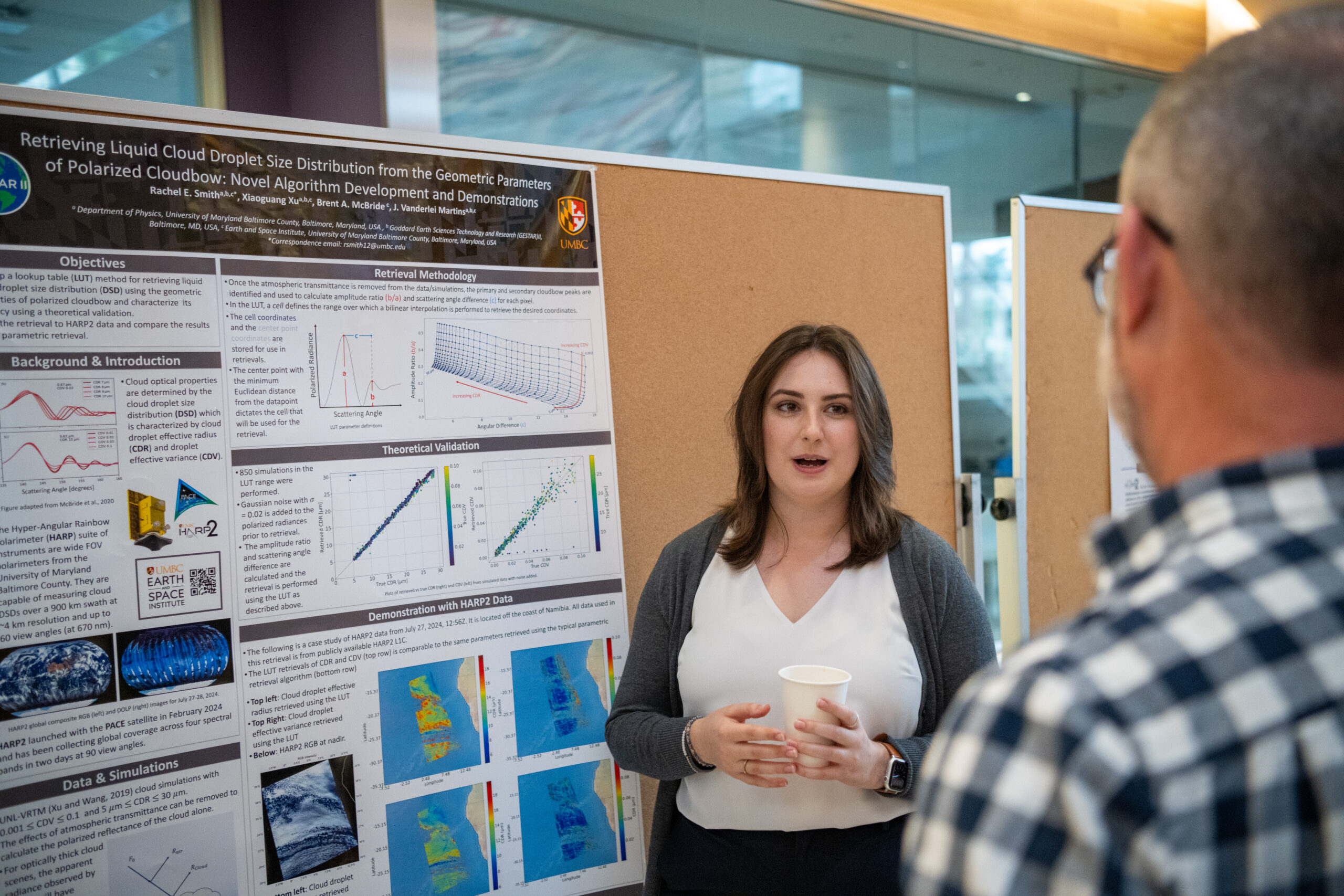woman speaks to man in front of a research poster