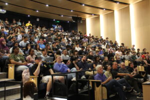 A lecture hall filled with hundreds of people in tiered seating