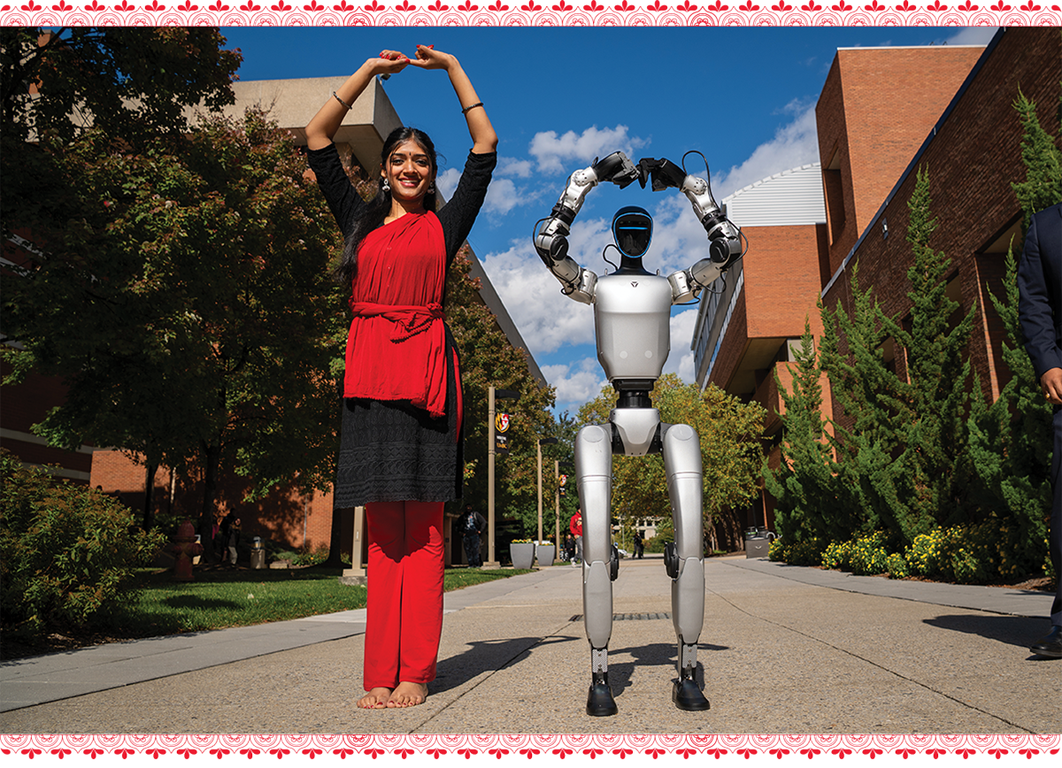 a young indian woman in red draped clothing, posing with a robot dance partner, arms above their heads