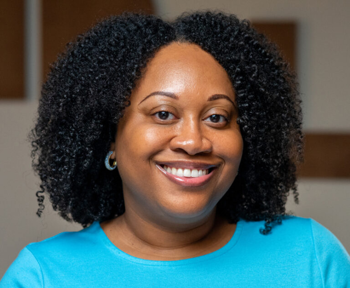 Headshot of a person with curly hair smiling.