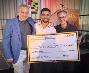 Three men pose for camera while holding an oversized check